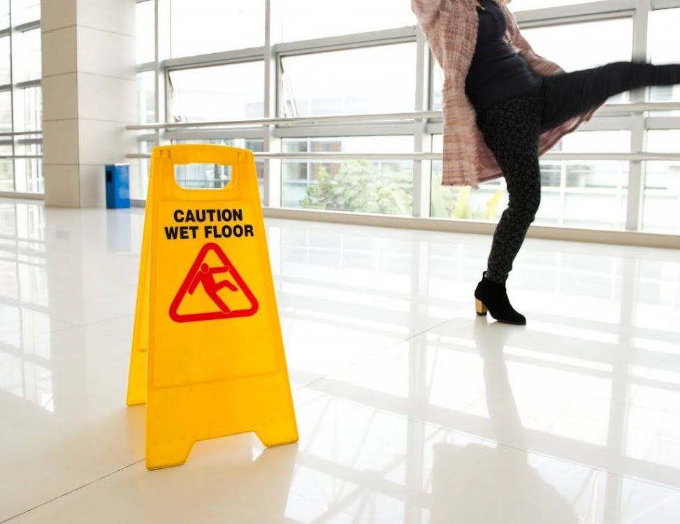 A woman is falling on a wet floor next to a caution wet floor sign.