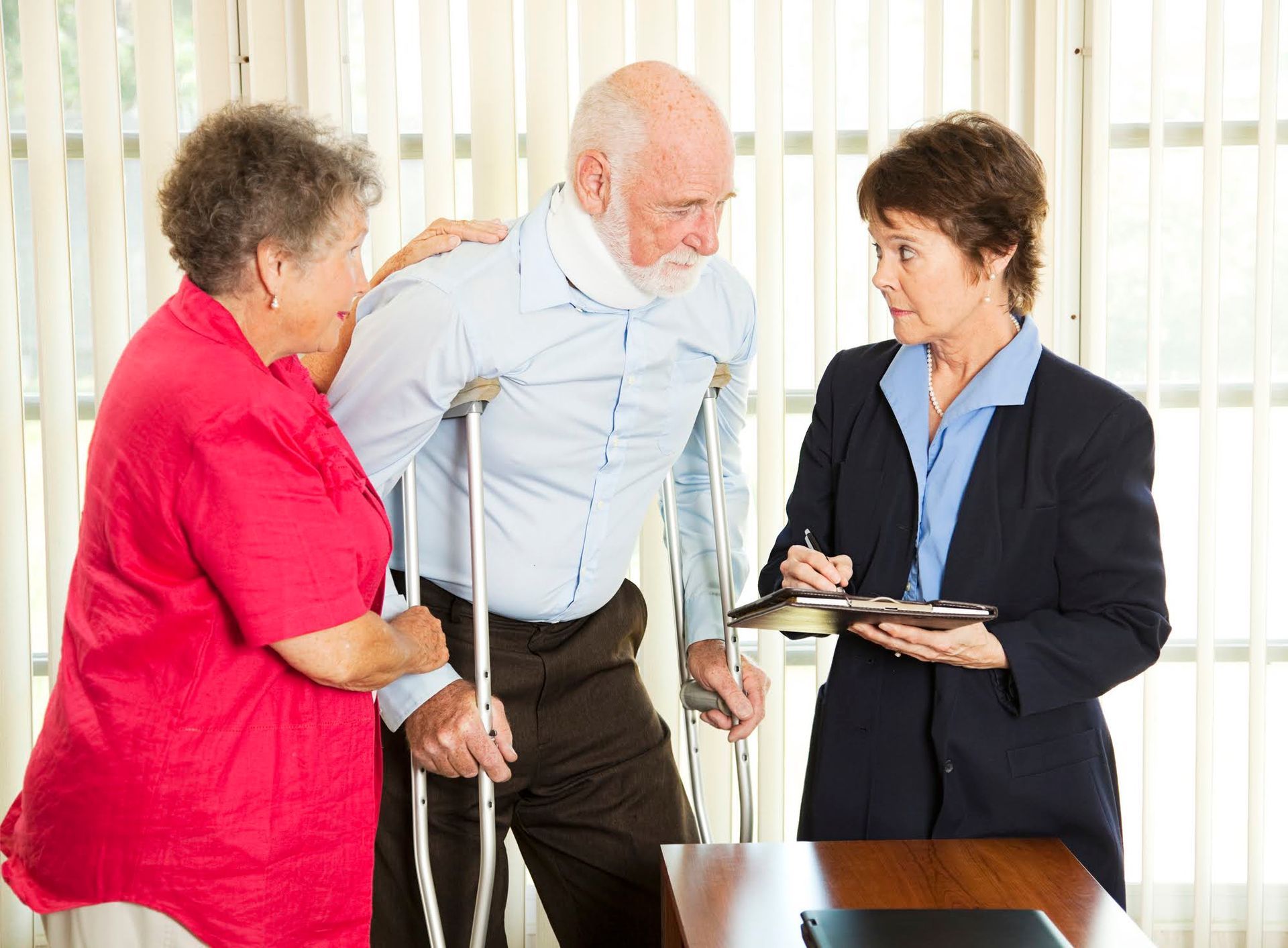 A man with crutches is talking to a woman and a man with a neck brace.