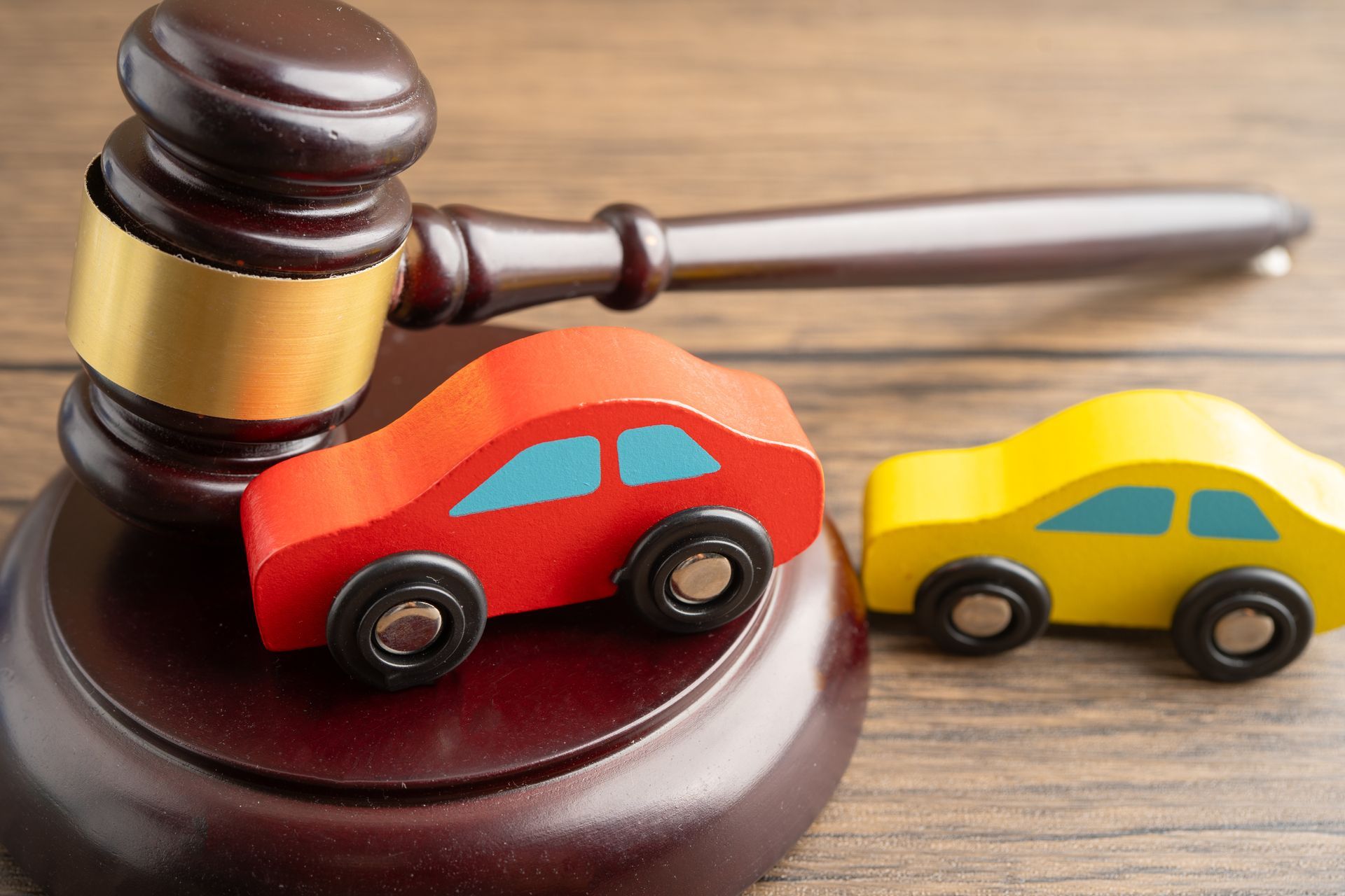 Wooden gavel beside red and yellow toy cars on a wooden surface. Wooden gavel beside red and yellow toy cars on a wooden surface.