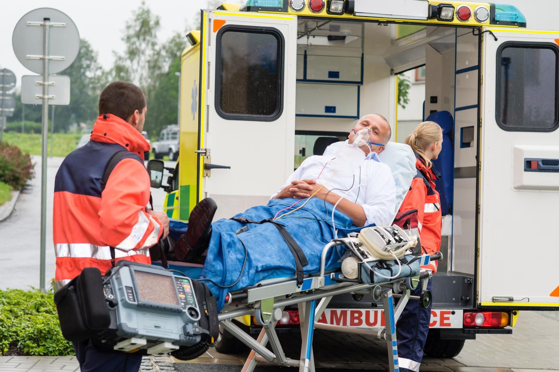 A man is being loaded into an ambulance on a stretcher.