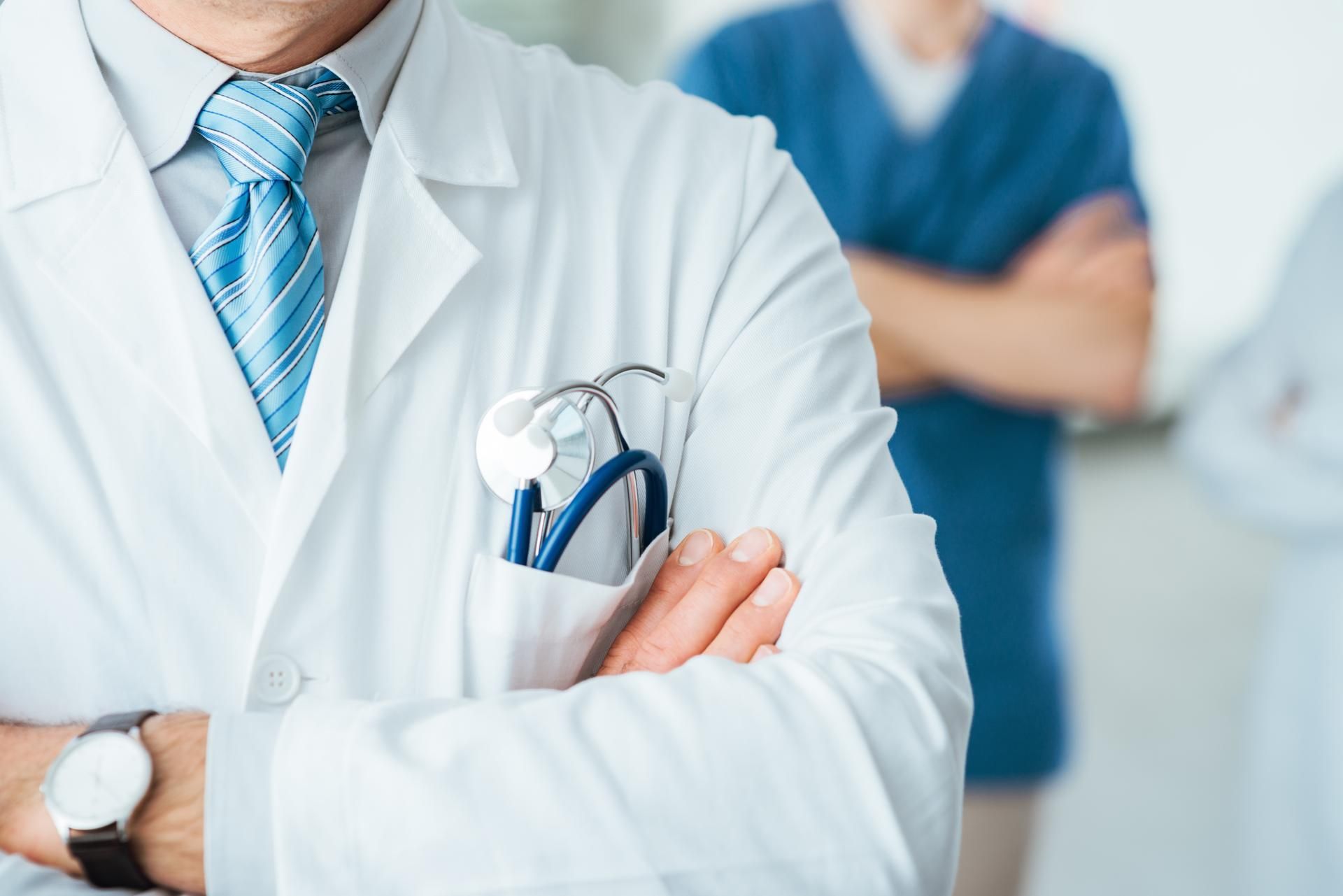 A doctor with his arms crossed and a stethoscope in his pocket.