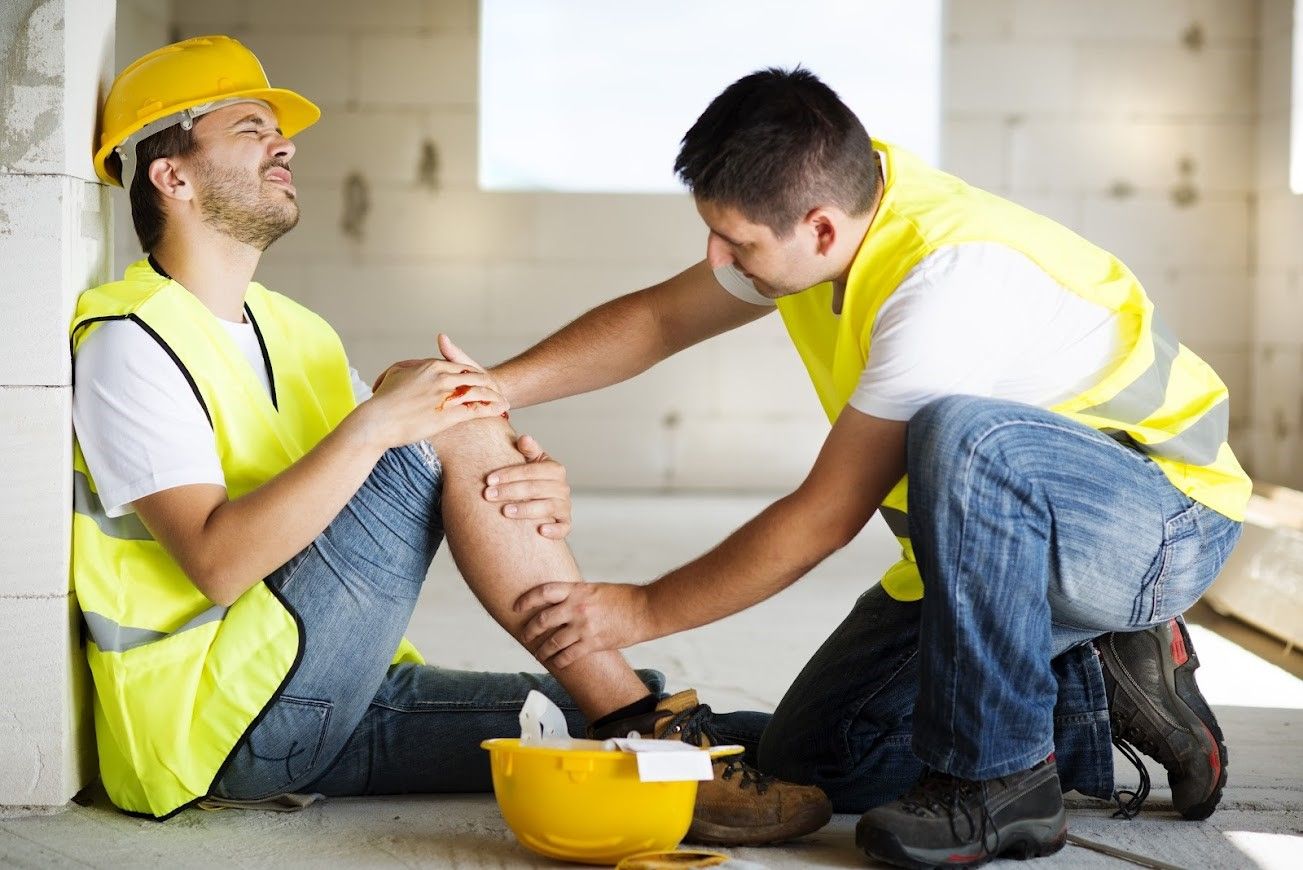 A man is kneeling down next to another man who has a knee injury.
