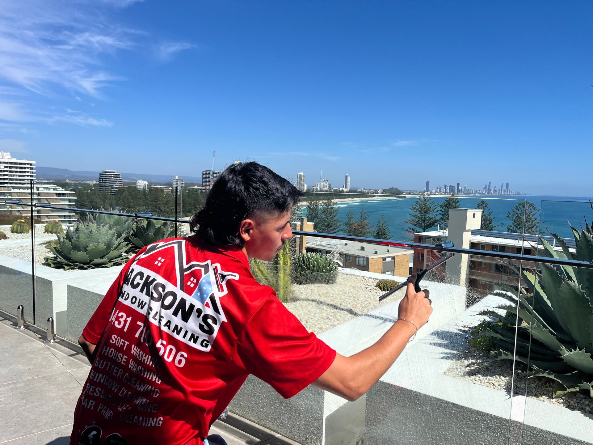 Man in Red Shirt Filming Coastal View With a Phone — Jackson's Window Cleaning in Nerang, QLD