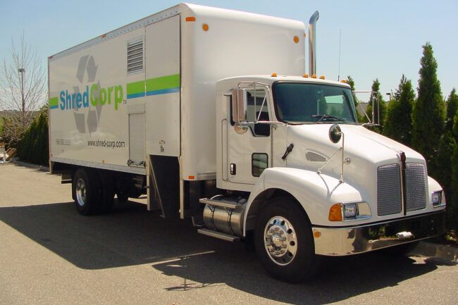 A white shred corp truck is parked in a parking lot