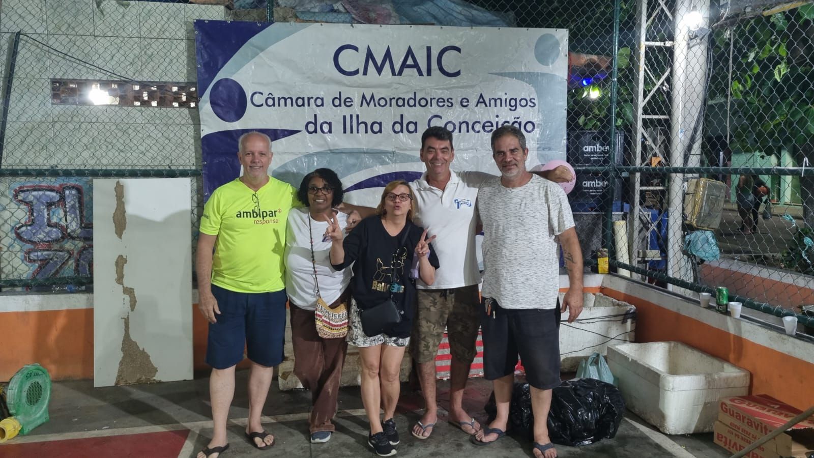 Um grupo de pessoas está posando para uma foto em frente a uma placa de cmaic.