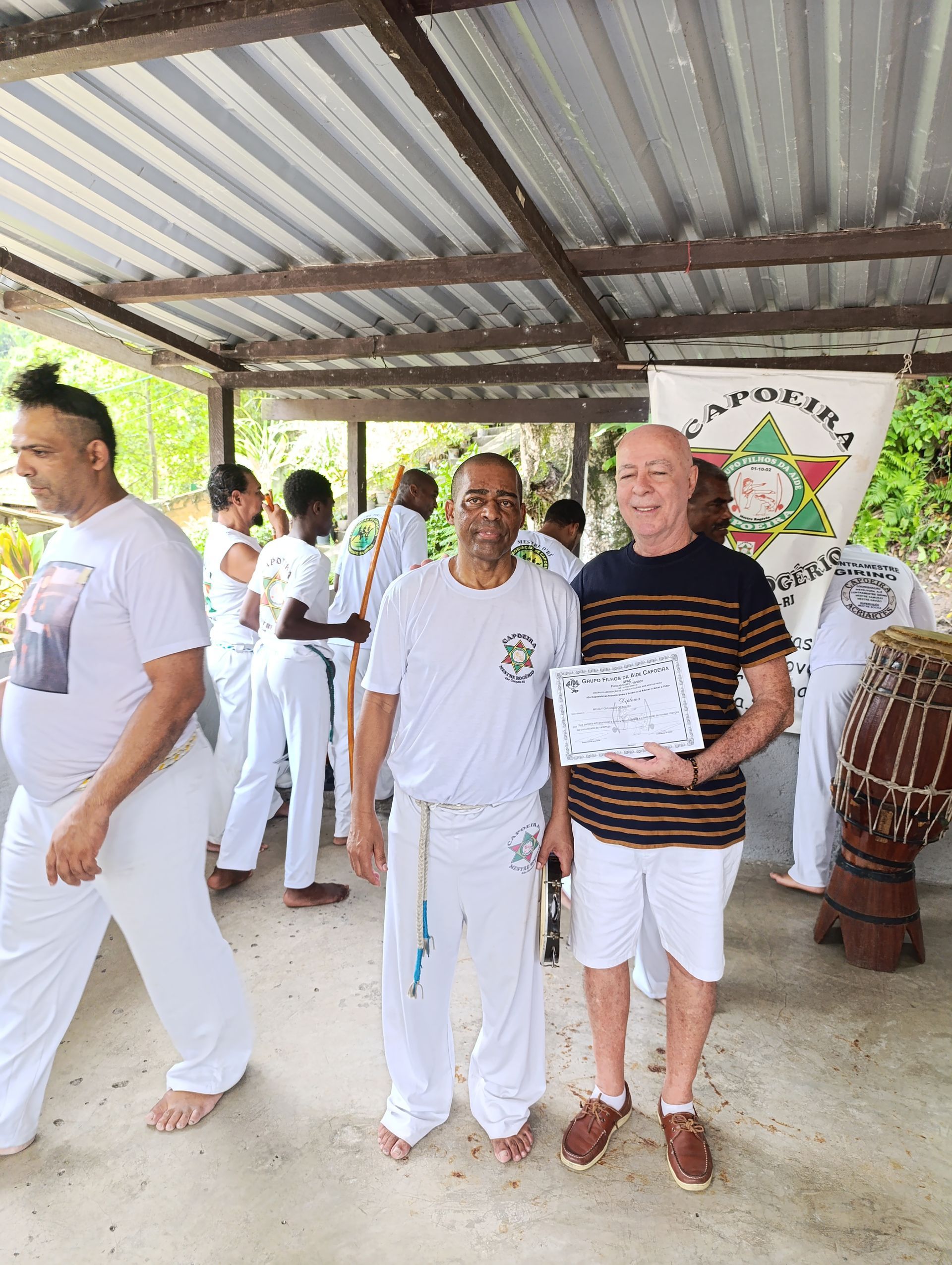 Um grupo de homens está de pé sob um telhado segurando um certificado.