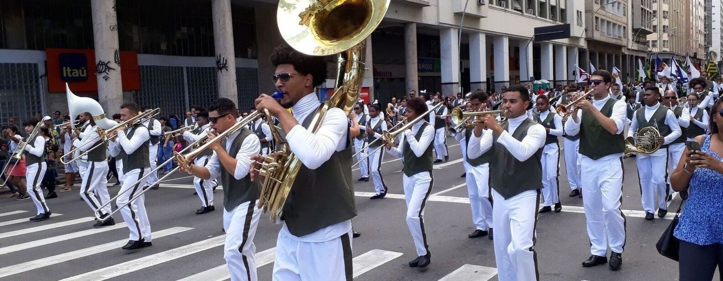 Uma banda está marchando pela rua em um desfile.