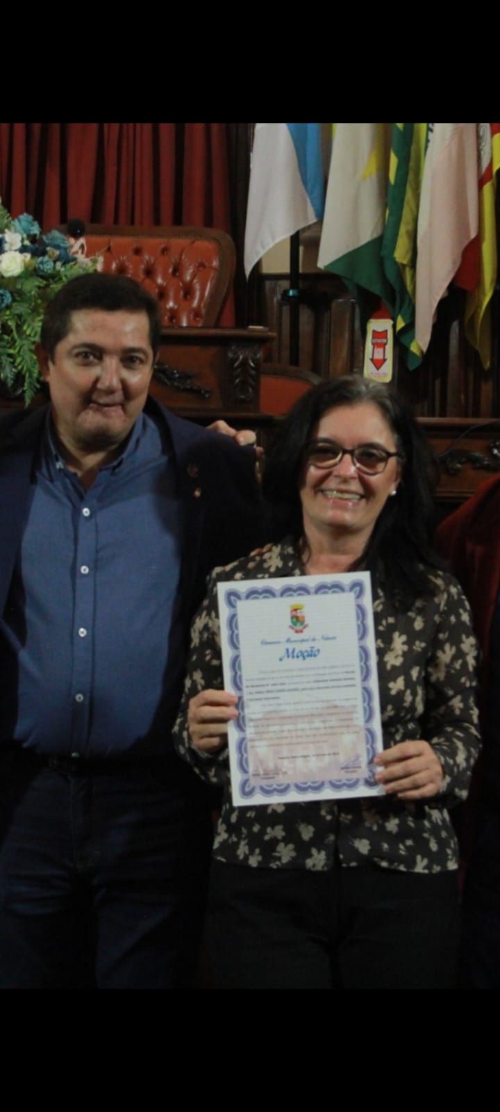 Um homem e uma mulher estão de pé, um ao lado do outro, segurando um certificado.
