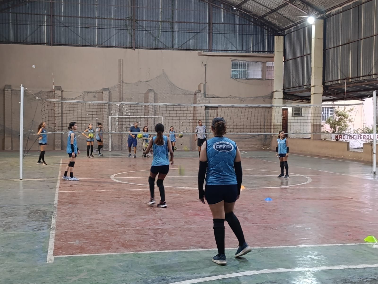 Um grupo de meninas está jogando vôlei em um ginásio.