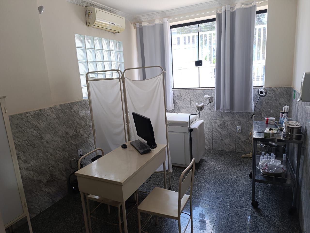 Um consultório médico com mesa, cadeira e computador.
