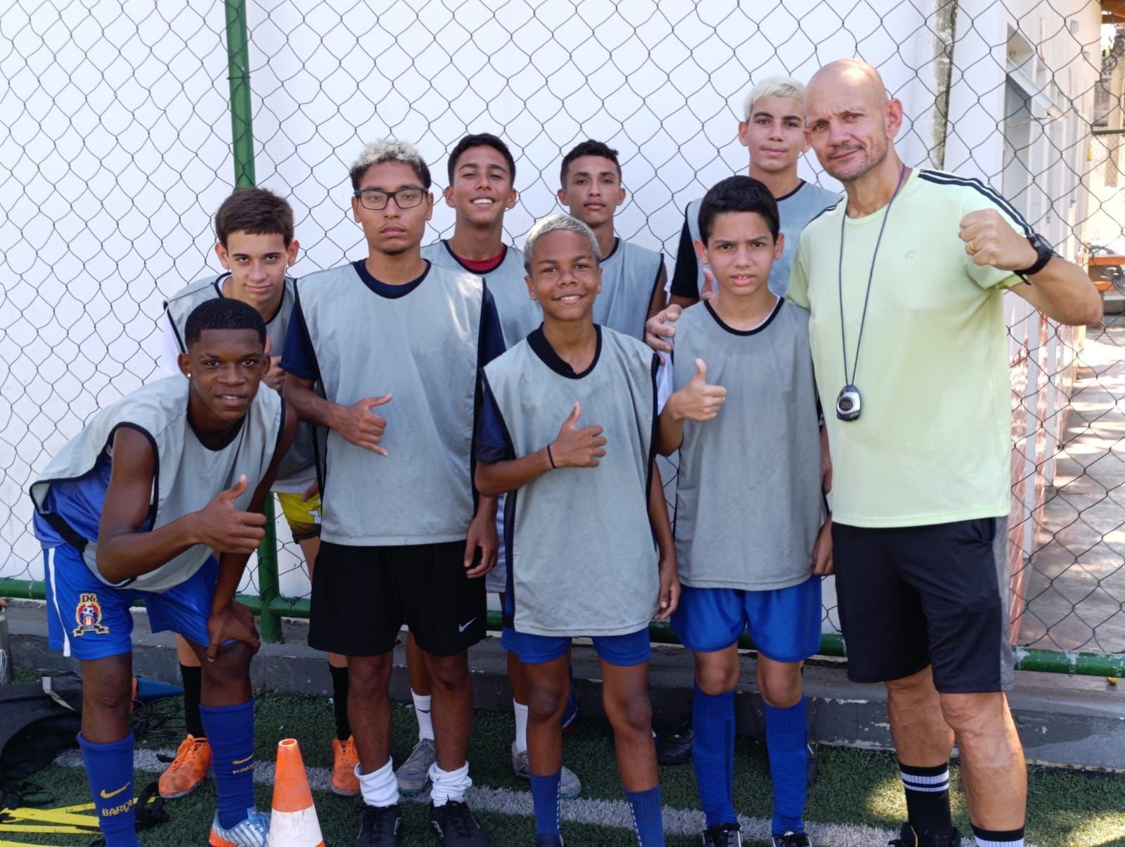 Um grupo de jovens rapazes está posando para uma foto com seu treinador.