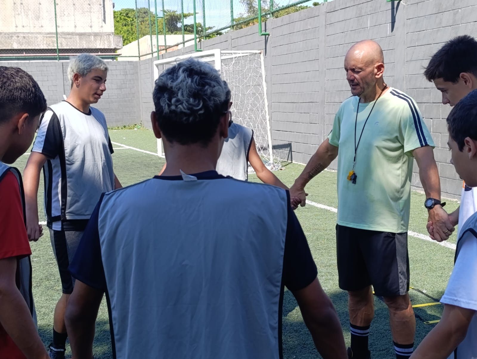 Um grupo de homens está em pé em um círculo em um campo de futebol