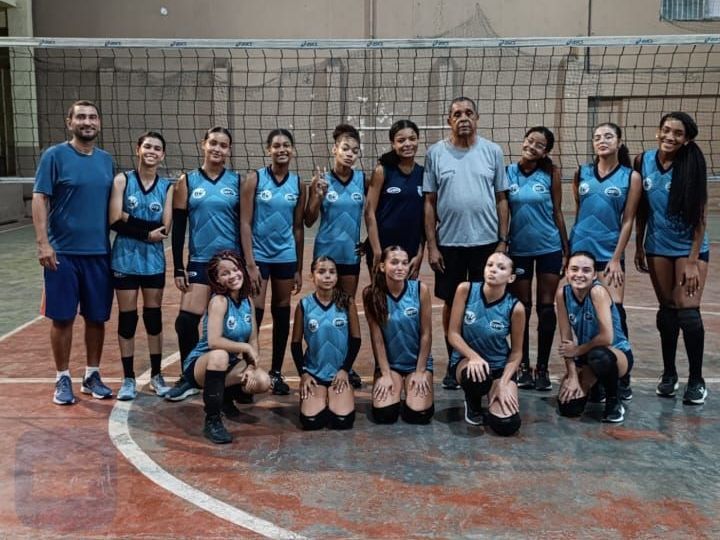 Um grupo de jogadores de vôlei está posando para uma foto em uma quadra.