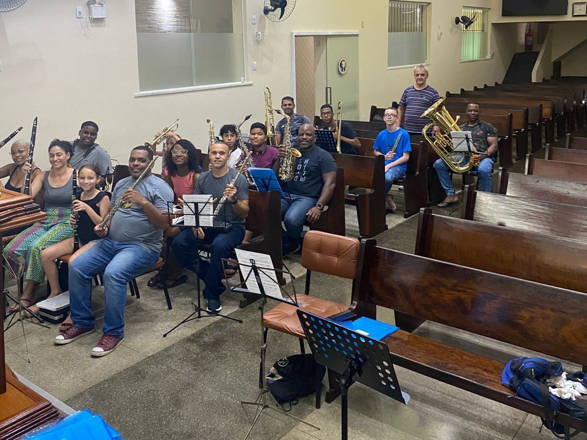 Um grupo de pessoas está sentado em uma igreja tocando instrumentos.