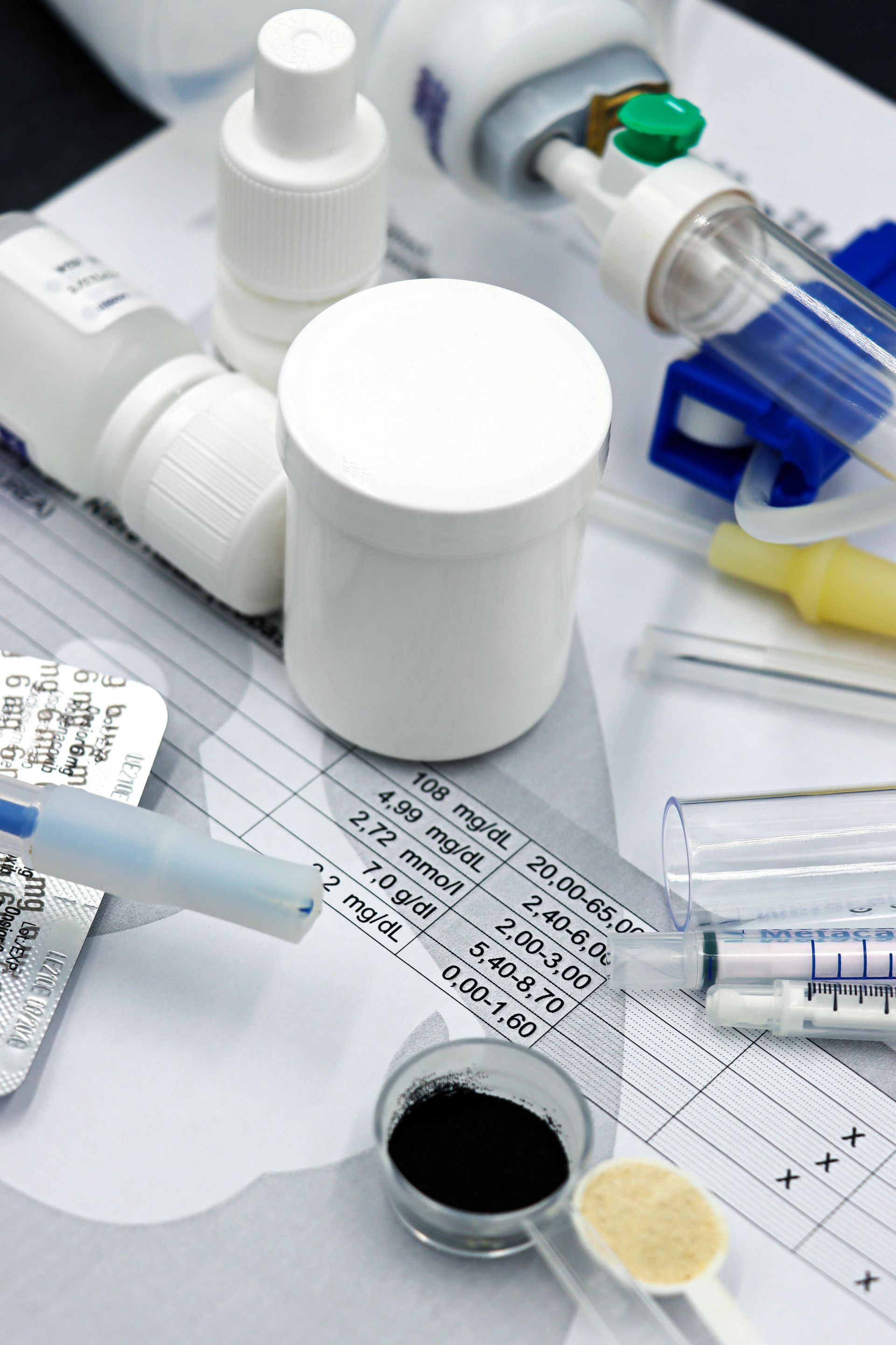 Scattered medicine bottles, pills, syringes, and lab samples on a medical chart