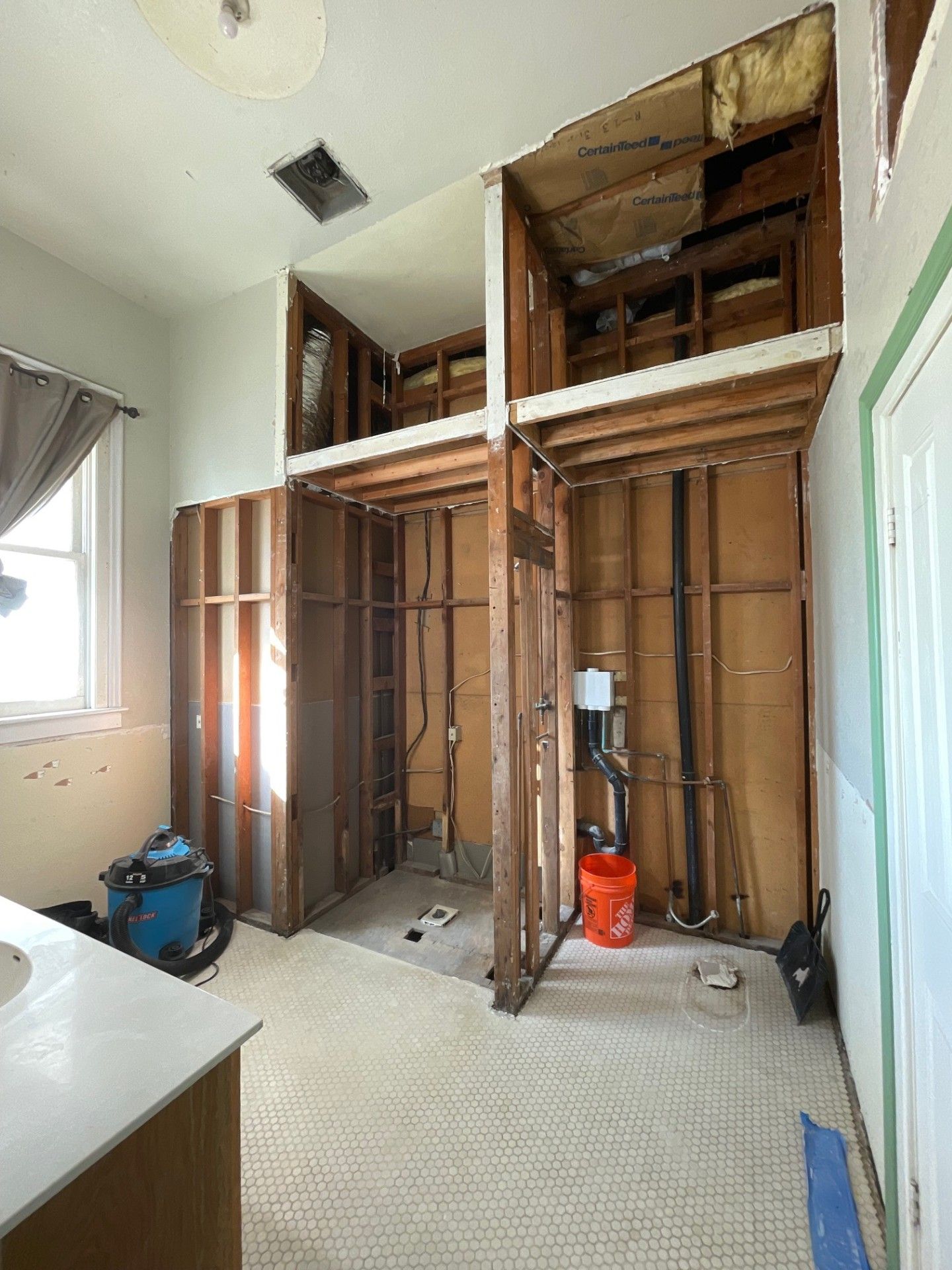 Bathroom under renovation with exposed wall studs and plumbing. Light, airy space with open walls.