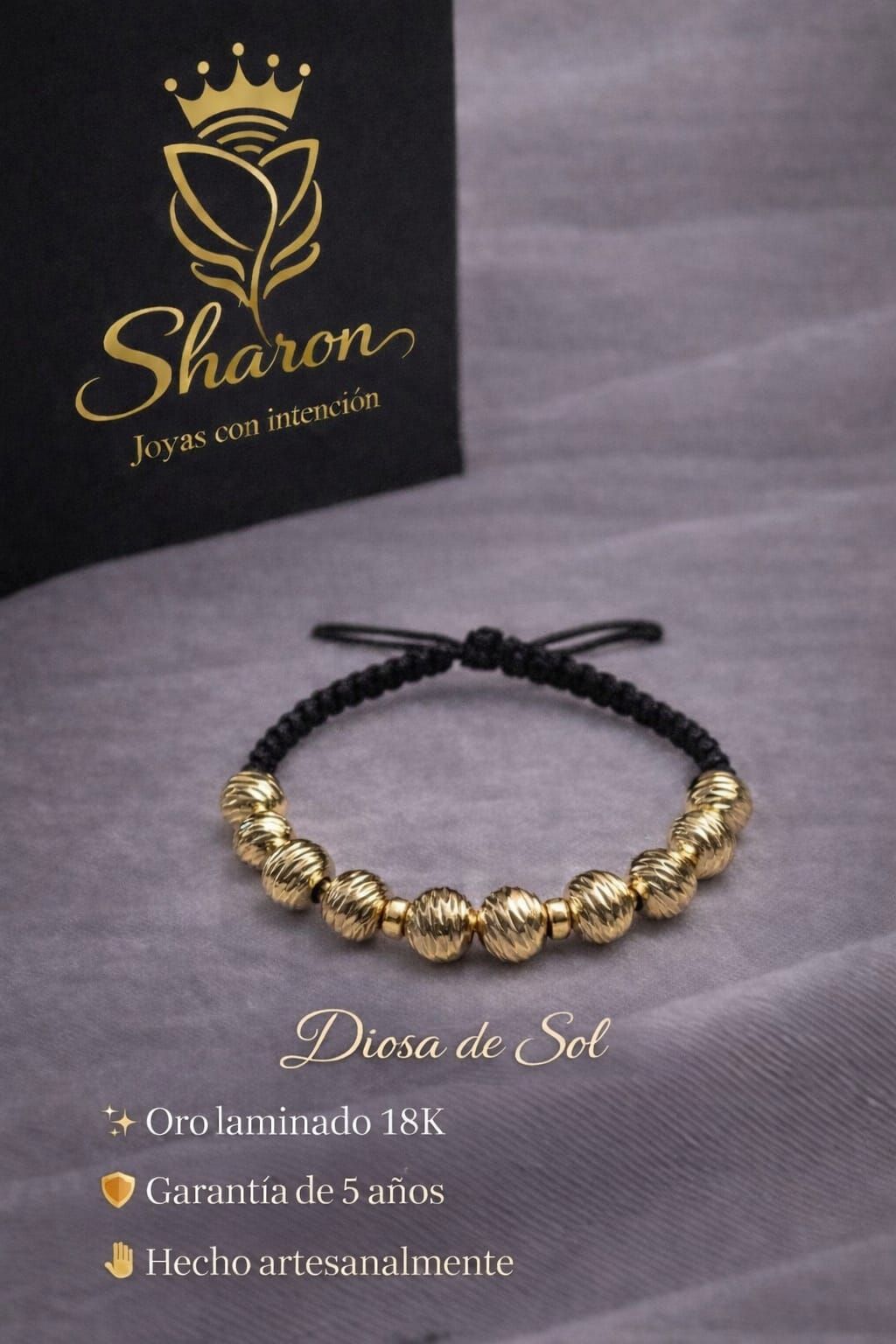 Pulsera con cuentas doradas y cordón negro sobre fondo de tela gris