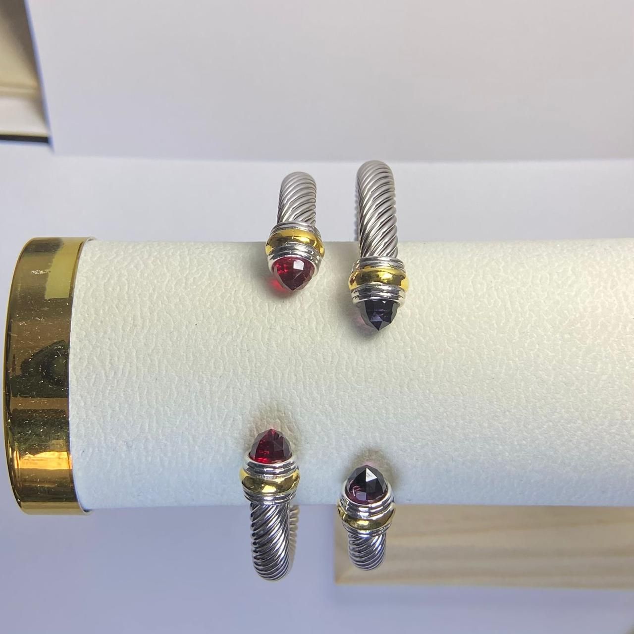 Dos pulseras plateadas estilo cable con detalles dorados y piedras preciosas