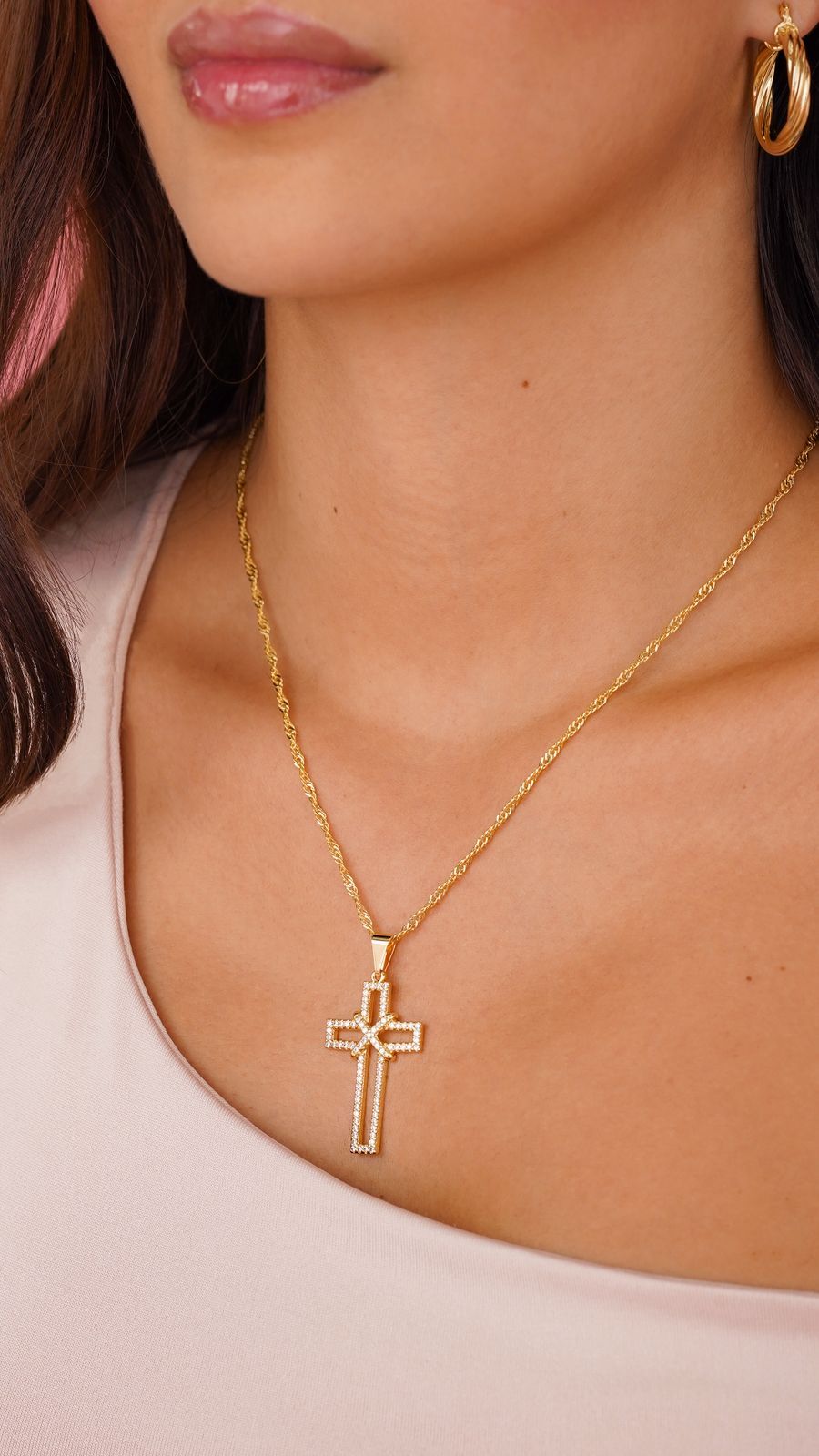 Un collar con colgante de cruz de oro que se lleva en una cadena pegada al pecho