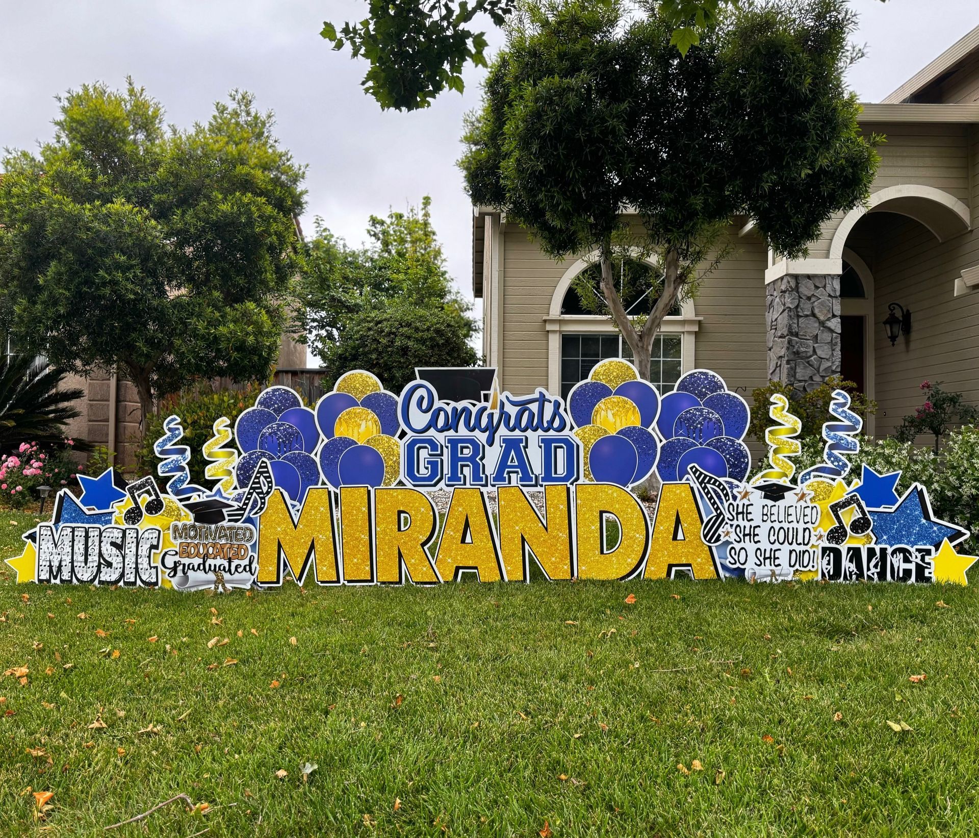 Deluxe graduation display in blue and gold. Congrats Grad Miranda appears. Graphics of interest in music and dance. 