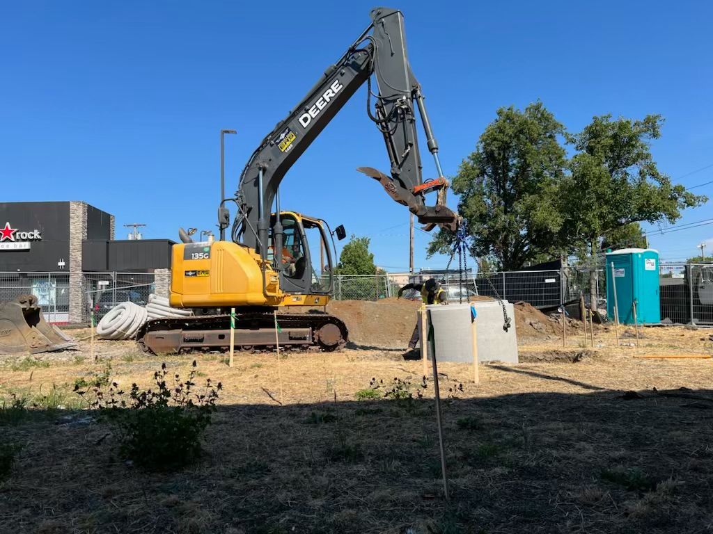 A yellow excavator is sitting on top of a pile of gravel.