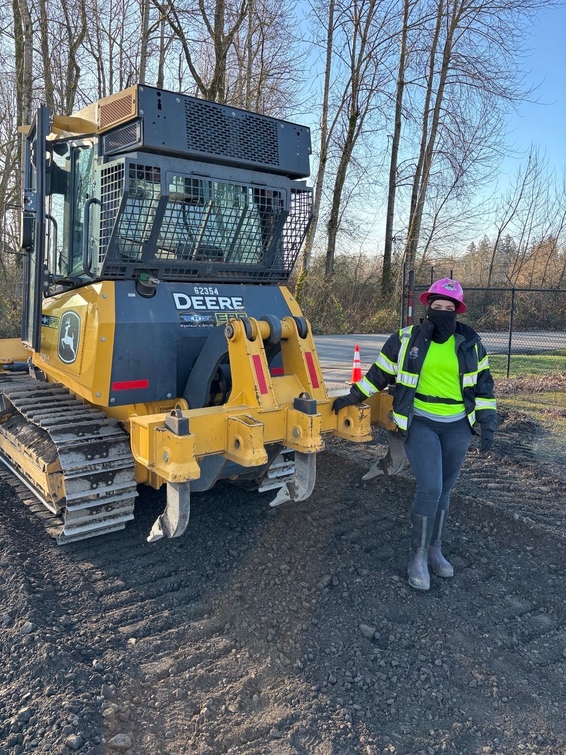 A yellow bulldozer is loading a pile of grass in a dirt field.