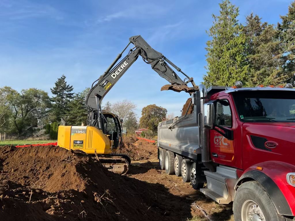 A large orange excavator is parked in the middle of a dirt field.