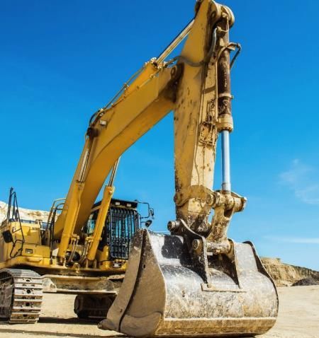 A bulldozer is driving down a dirt road in the middle of a forest.