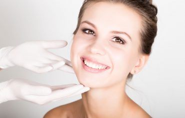 A woman is smiling while getting a botox injection in her face.