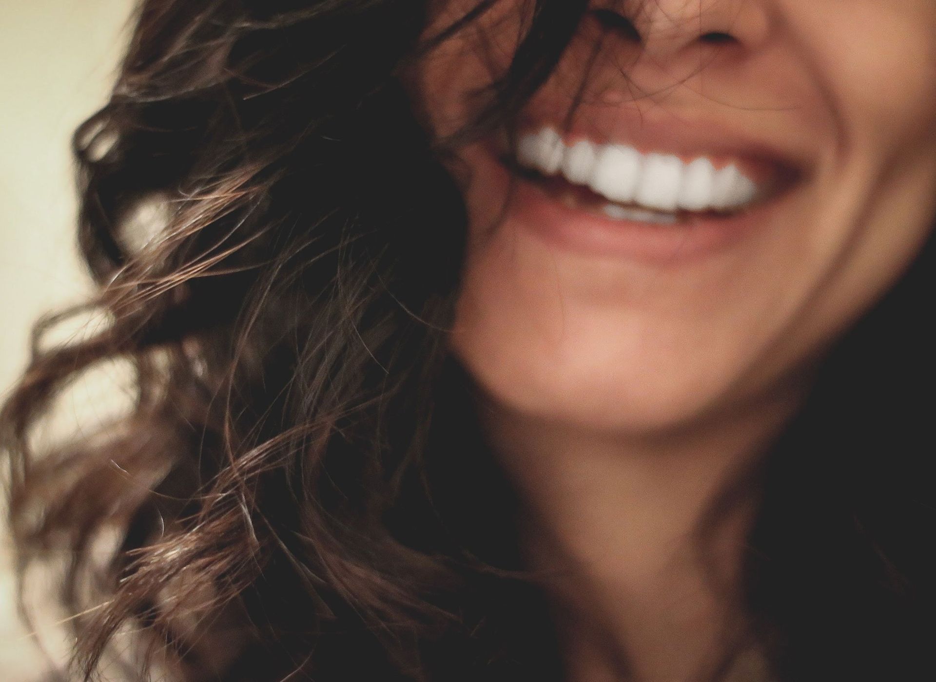A woman is smiling with her hair blowing in the wind.
