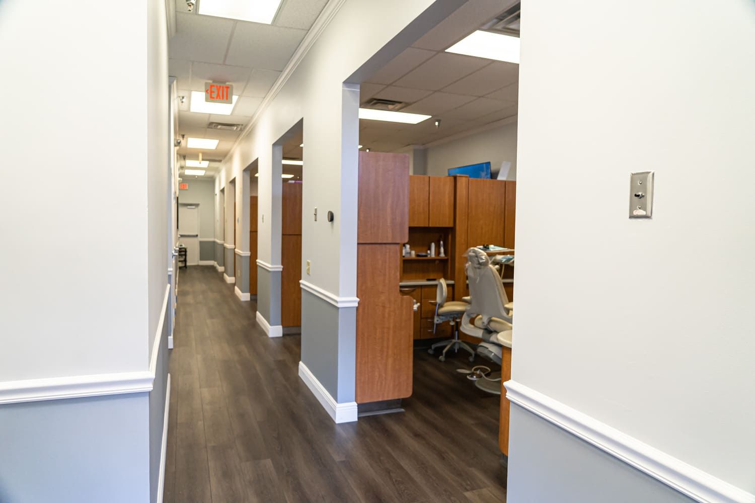 A long hallway in a dental office with wooden floors and cabinets.