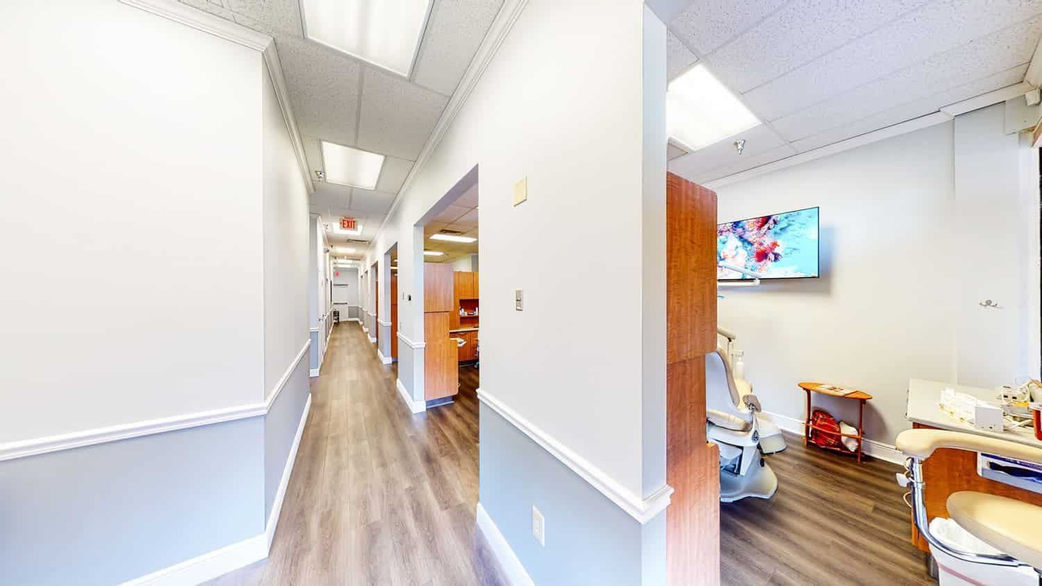 A long hallway leading to a dental office with a dental chair.