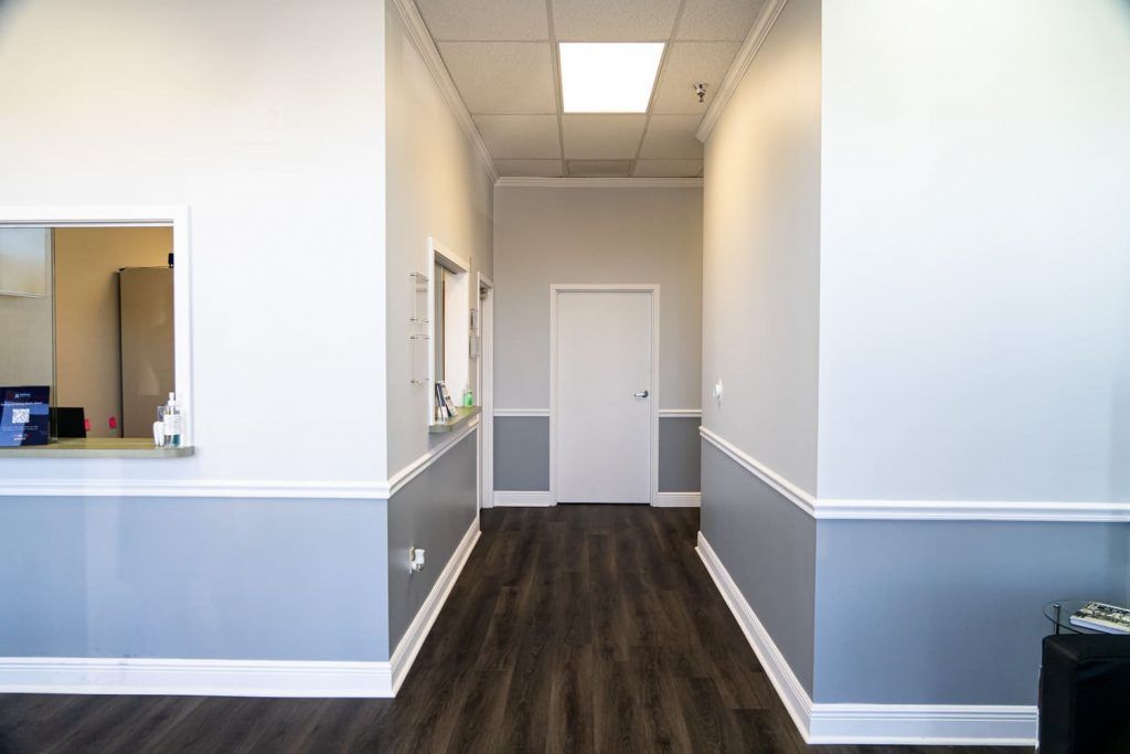 A long hallway in a building with a wooden floor and white walls.