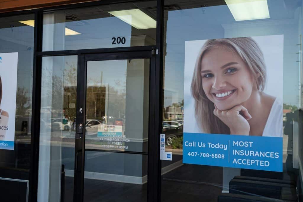 A store front with a picture of a smiling woman on the window.