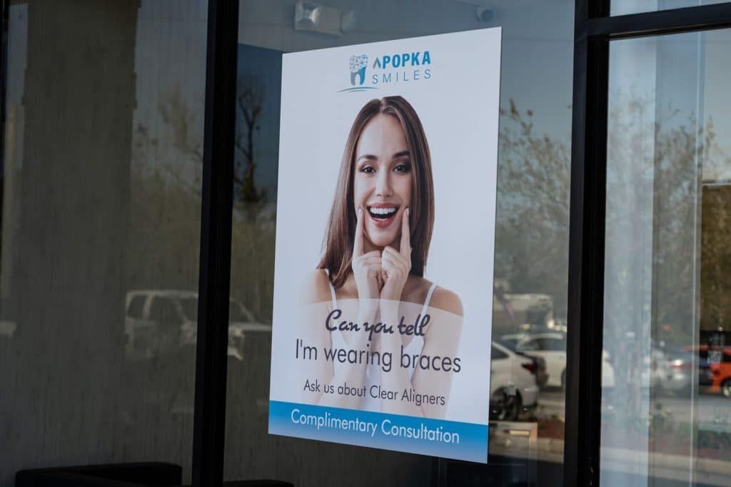 A poster of a smiling woman is hanging on a window.