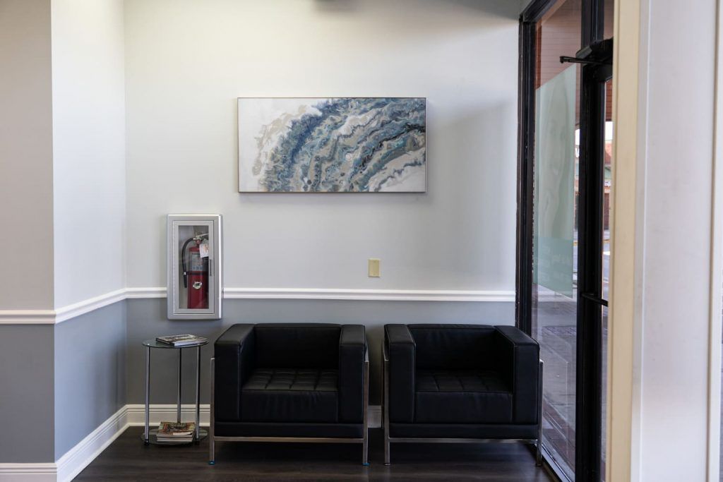 A waiting room with two chairs and a painting on the wall.