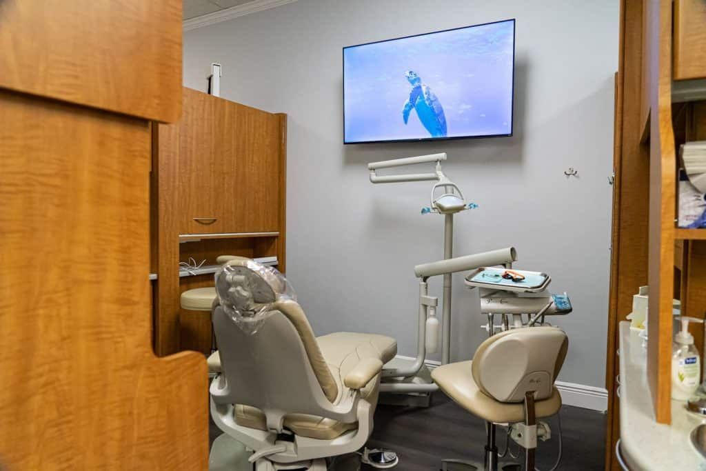 A dental office with a dental chair and a television on the wall.