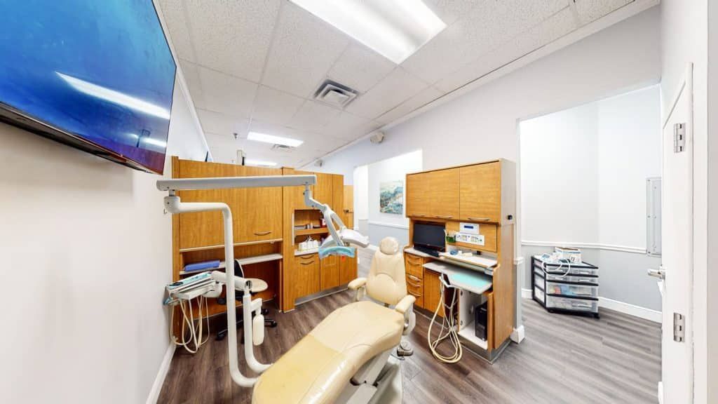 A dental office with a dental chair and a television on the wall.