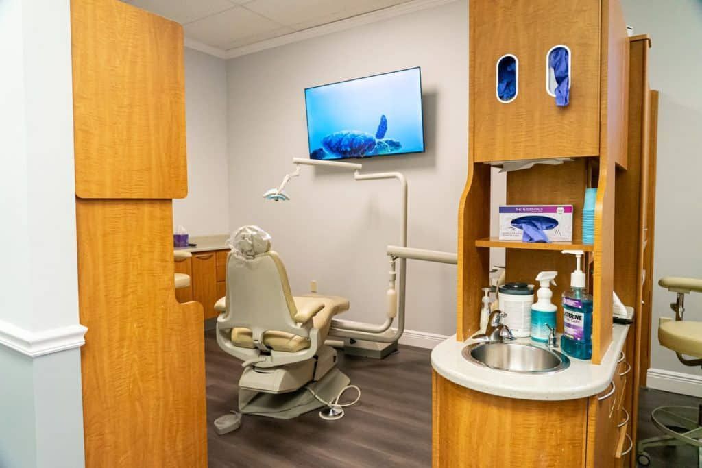 A dental office with a dental chair and a sink.