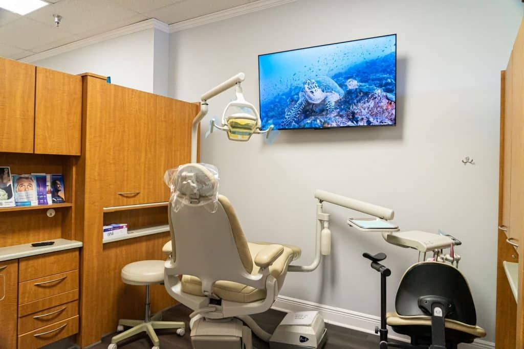 A dental office with a dental chair and a flat screen tv on the wall.