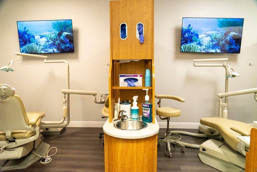 A dental office with two dental chairs and a sink.