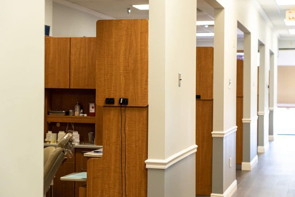 A long hallway in a dental office with wooden cabinets and a dental chair.