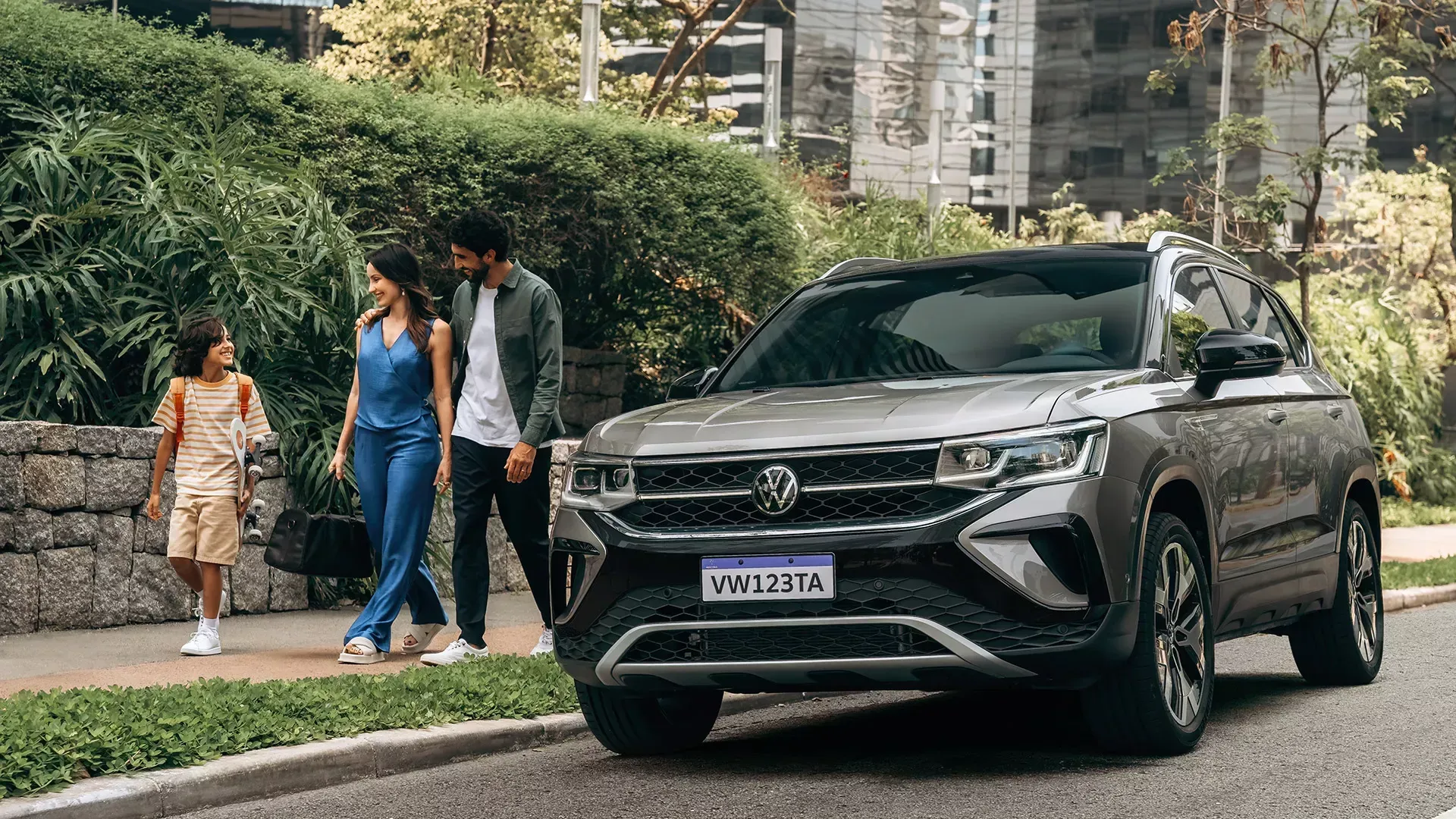 SUV preto estacionado em uma rua arborizada ao lado de duas pessoas caminhando e uma criança por perto.