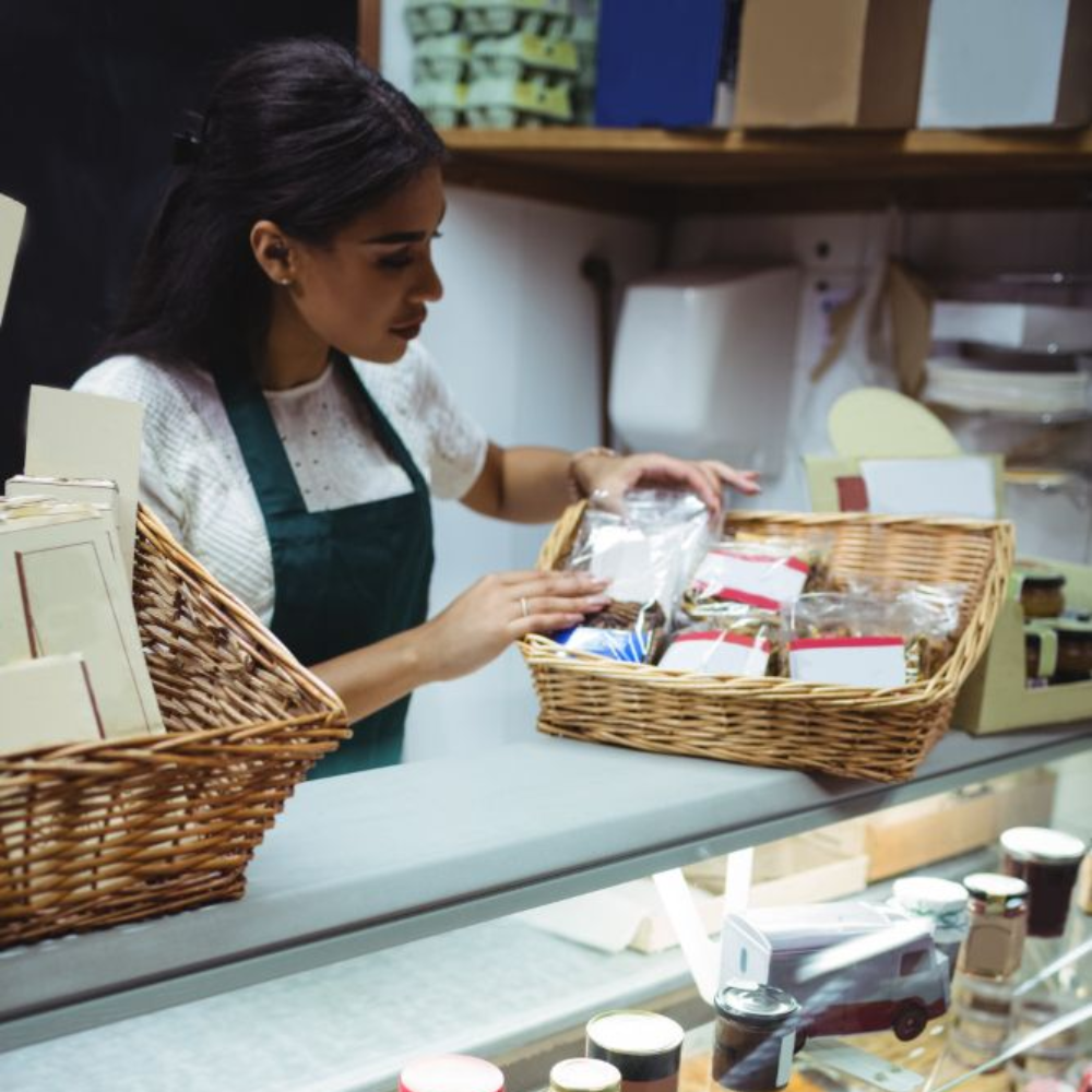 Shop clerk organizing packaged goods in wicker baskets at a counter in a store.