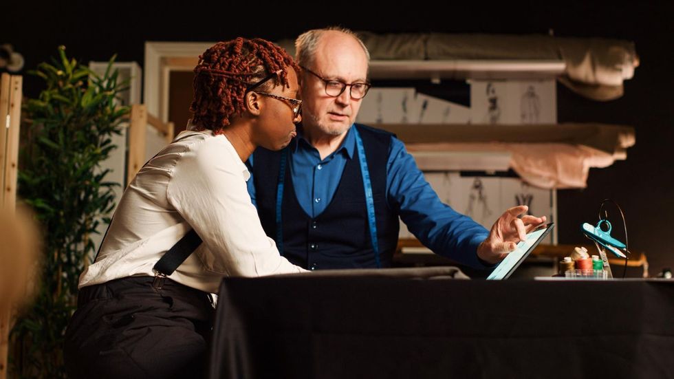 Business team in a meeting around a table in a sunlit office, discussing documents and laptops