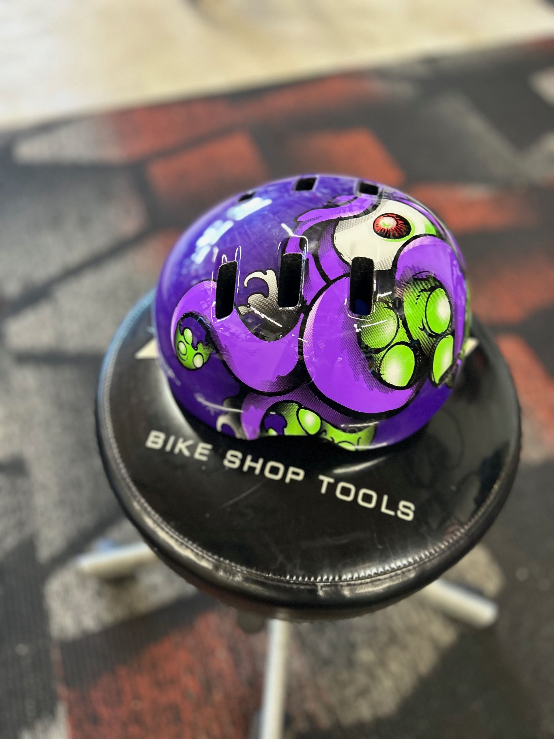 A purple helmet sits on a bike shop tools stool