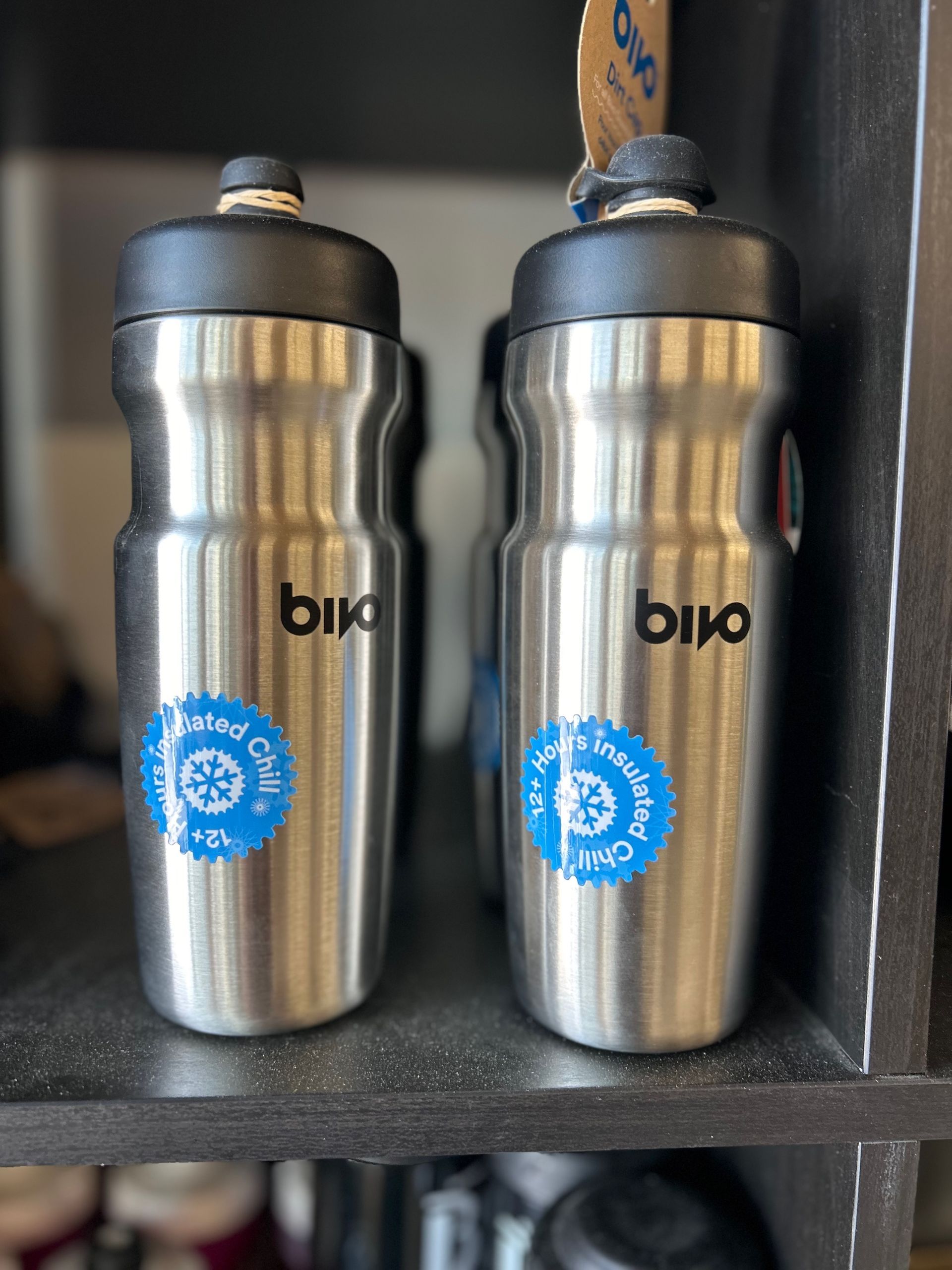 Two stainless steel water bottles are sitting on a shelf.