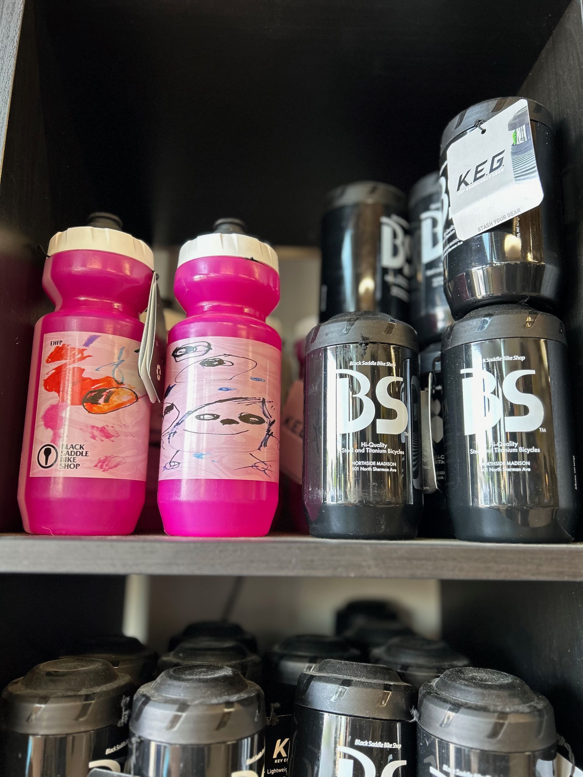 A shelf filled with pink and black water bottles.