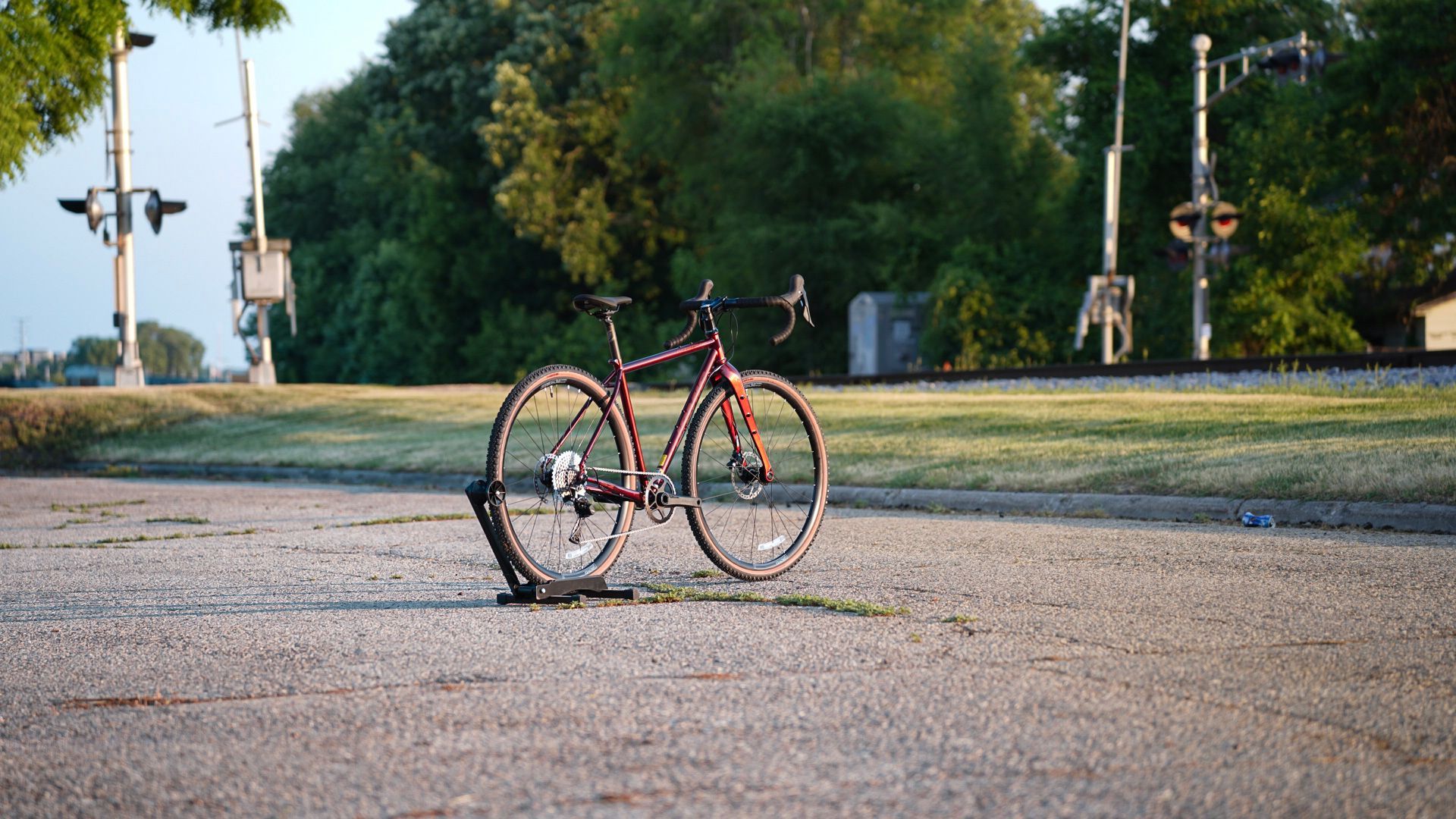 A bicycle is parked on the side of the road next to a railroad track.