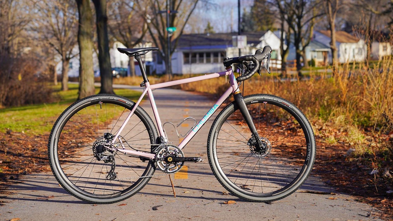A pink bicycle is parked on the side of a road.